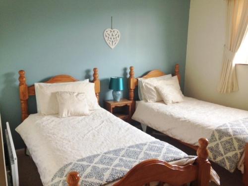 1 dormitorio con 2 camas con edredones blancos en The Haven, en Rothbury
