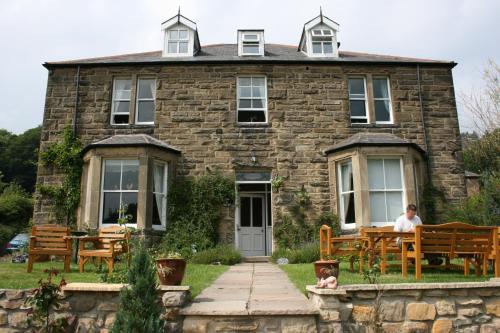 a man sitting on a bench in front of a stone house at The Haven in Rothbury