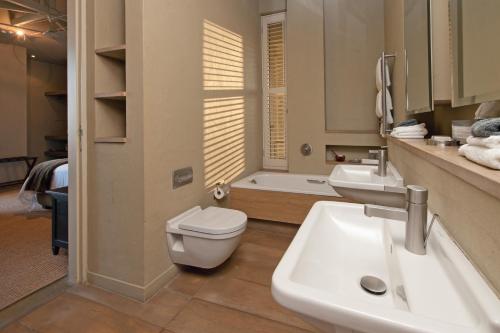 a bathroom with a sink and a toilet and a tub at Mosselberg on Grotto Beach in Hermanus