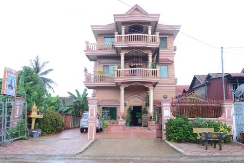 uma casa cor-de-rosa com uma varanda numa rua em Javier Guesthouse em Tbeng Meanchey