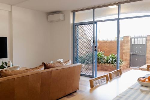 ニューカッスルにあるBeachfront Getaway with Views, Pool & Tennis Courtのリビングルーム(ソファ付)、大きなスライド式ガラスドア