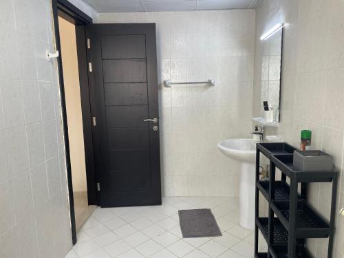 a bathroom with a black door and a sink at Ladies only Feel like at home, among sisters in Ajman