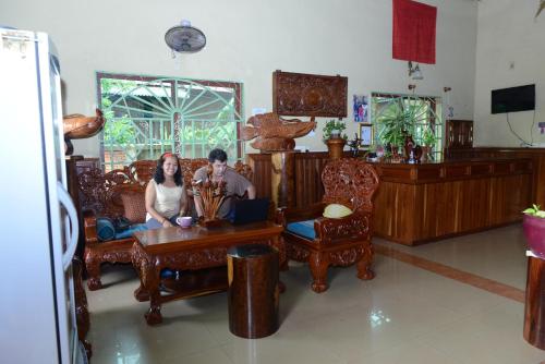 a man and woman sitting at a table in a room at Javier Guesthouse in Tbeng Meanchey