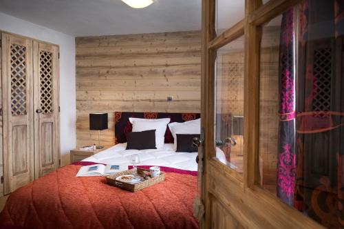 1 dormitorio con 1 cama grande y pared de madera en CGH Résidences & Spas Les Chalets de Léana en Les Carroz d'Araches