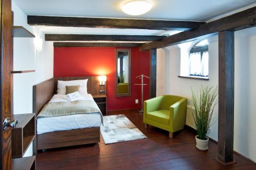 a bedroom with a bed and a green chair at Hotel U Hada Žatec in Žatec