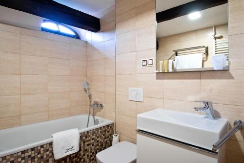 Hotel U Hada Žatec في زاتيك: حمام مع حوض وحوض استحمام ومرحاض