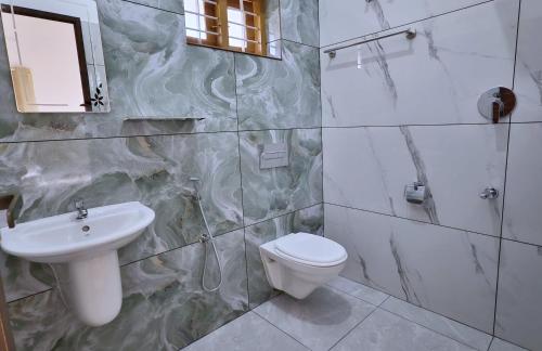 a bathroom with a sink and a toilet and a mirror at Gypsy Walker Plus in Varkala