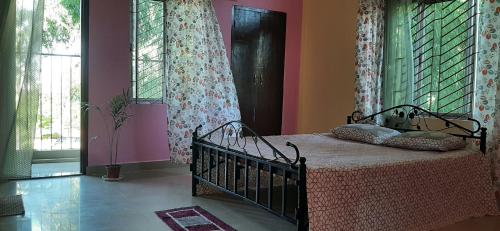 a bedroom with a bed with pink walls and windows at Peace Abode Vista in Dibrugarh