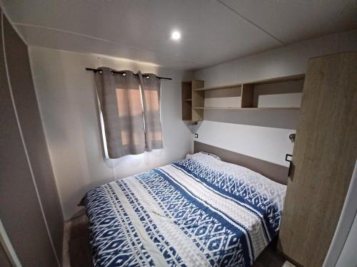 Un dormitorio con una cama con una manta azul y blanca. en Mobilhome 3 chambre à 2 pas de la plage, en Sarzeau