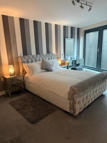 a bedroom with a large bed with striped walls at Bond Street Luxury Apartment Central Chelmsford in Chelmsford