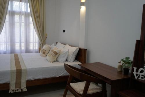 a bedroom with a bed with a desk and a window at Avira Cozy Corner in Kilinochchi