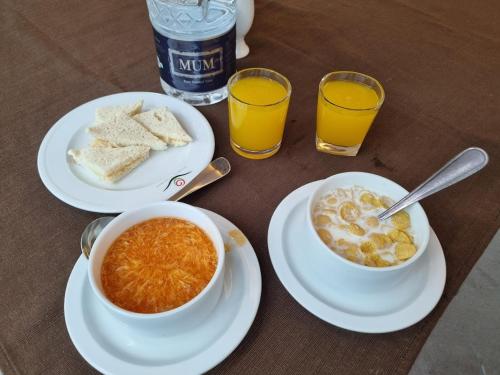 una mesa con dos platos de comida y dos vasos de zumo de naranja en Aristocrat Inn - Lake Park & USA club, en Dhaka