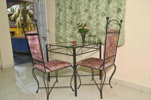 Una mesa de cristal con dos sillas y una mesa de cristal con flores. en Libton Manor, en Candolim