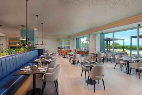 a restaurant with tables and chairs and windows at Delta Hotels by Marriott Azores in Ponta Delgada