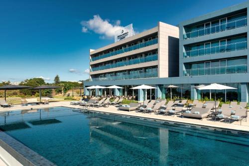a hotel with a swimming pool and chairs and a building at Delta Hotels by Marriott Azores in Ponta Delgada