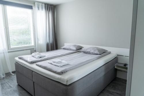 a large bed in a white room with a window at Apartment Siihtala - suuri saunallinen huoneisto in Joensuu