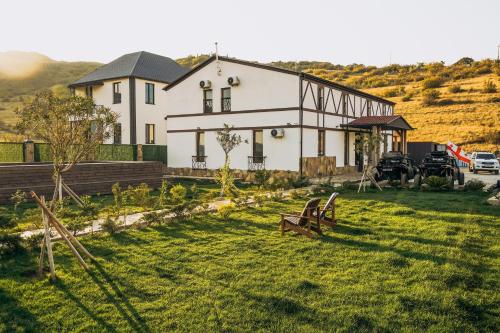 une maison blanche sur une colline avec une cour d'herbe dans l'établissement Camp Hotel Pura Vida, à Tbilissi