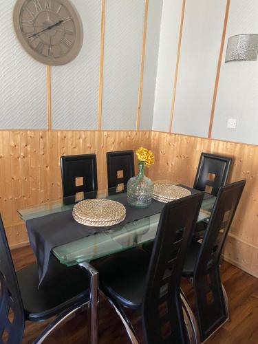 une table à manger avec des chaises et une horloge murale dans l'établissement Georges holiday apt the blue suite, à Inverness