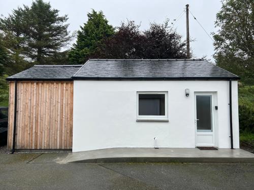 a small white shed with a wooden building at Scandi style Cottage by the sea, Isle of Skye in Portree