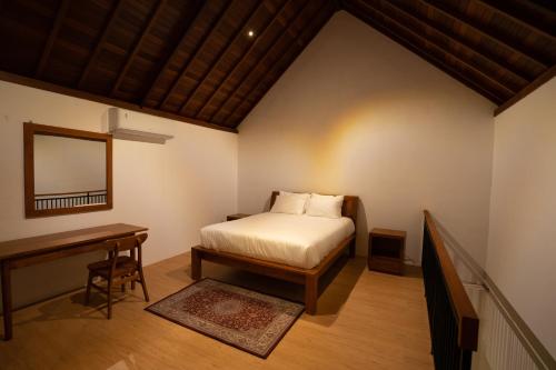 Un dormitorio con una cama, un escritorio y un espejo. en De Awan Villa, en Kerobokan