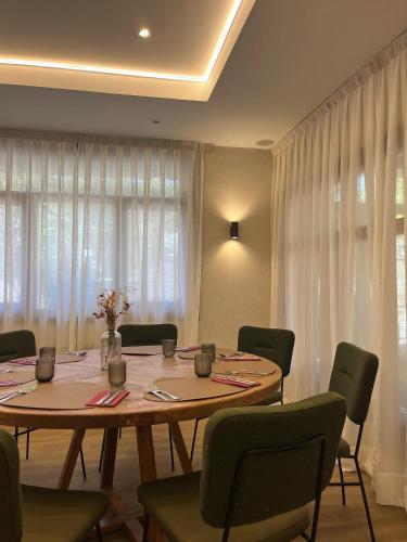 Un comedor con mesa y sillas y cortinas. en Hotel Rural Spa & Wellness Hacienda Los Robles, en Navacerrada