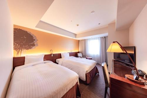 a hotel room with two beds and a television at Hotel Keihan Sapporo in Sapporo