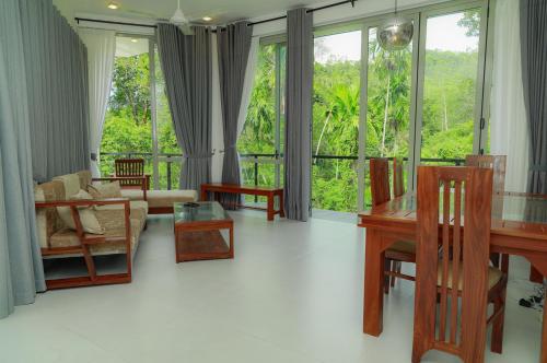 a living room with a table and chairs and windows at River View Stay in Latpandura