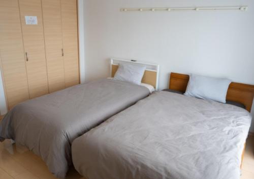 two beds sitting next to each other in a bedroom at apartment hotel myu in Mito
