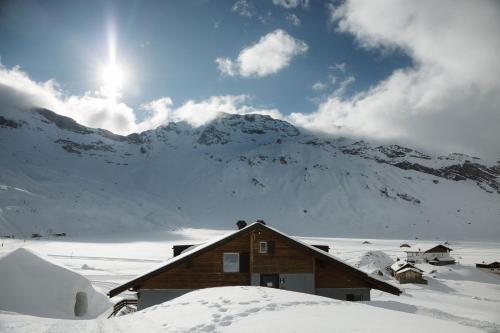 a house in the snow with a mountain in the background at Berghotel Engstligenalp Adelboden in Adelboden