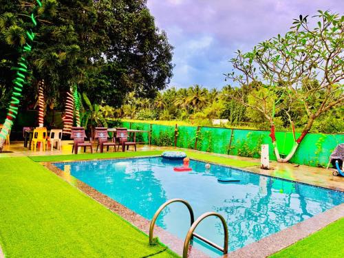 a swimming pool in a yard with a green fence at Oceanwood Beachfarm Alibaug in Nagaon