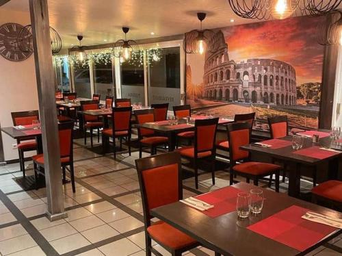 a restaurant with tables and chairs and a painting of the coliseum at Hôtel NOROTEL in Brumath