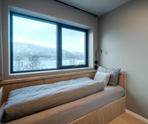 un lit dans une chambre avec une grande fenêtre dans l'établissement Staying Apt 5, à Tromsø