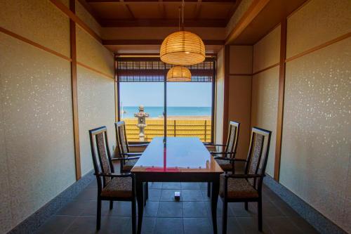 a dining room with a table and chairs and a view of the beach at 洗心和方 Senshin Waho in Awaji