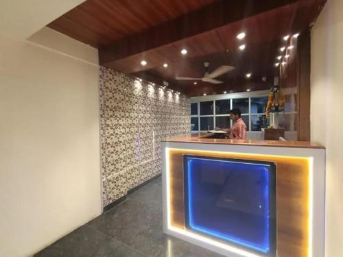 a man standing at a counter in a kitchen with a tv at Hotel Mood Premium By Glitz Hotels in Vasai