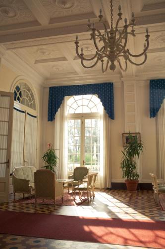 a room with a chandelier and chairs and a large window at Grand Hotel Cesenatico in Cesenatico