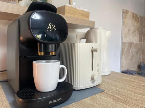 a coffee maker with a cup on a counter at eden & Spa in Gajan