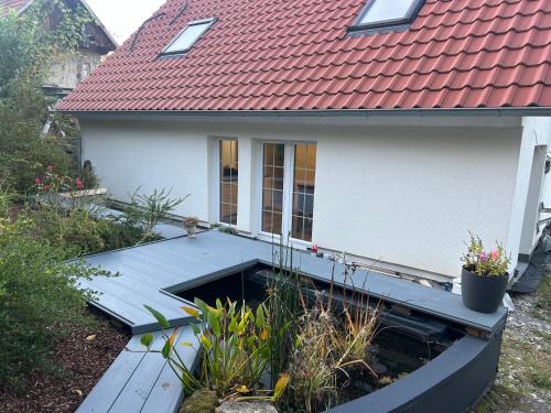 Neuensteinにあるdas HAUSの木製のデッキと赤い屋根のある家