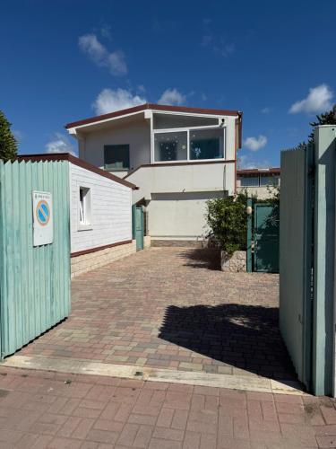 a white house with a gate and a brick driveway at Azure Oasis with parking near the airport & beach in Focene
