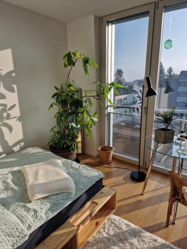 a bedroom with a bed and a balcony with plants at Lumi, modernes Attika-Refugium in Derendingen