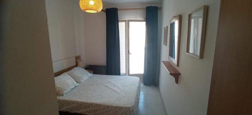 a bedroom with a bed and a window with blue curtains at Tramuntana Beach in Calafell