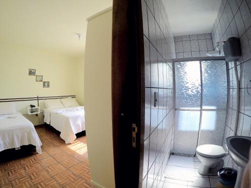 een slaapkamer met 2 bedden en een badkamer met een douche bij Hotel Schreiber in Rio do Sul