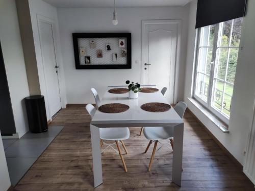 a white dining room with a white table and chairs at Maison indépendante proche de Liège -Séjour nature & confort in La Salle