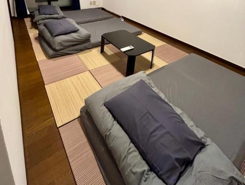 a room with three beds and a table at Guest House YADOKARI in Hirakata