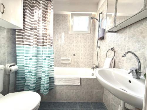 Un baño con lavabo, inodoro y bañera. en Onyx Beach Villa - Cozy 2BR - Walk to Beach, en Meneou