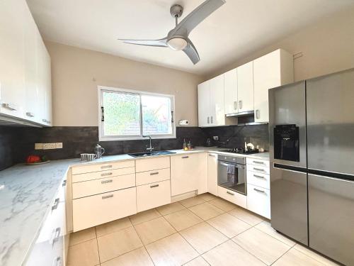 a kitchen with white cabinets and a ceiling fan at Onyx Beach Villa - Cozy 2BR - Walk to Beach in Meneou