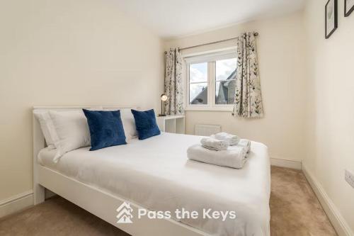Un dormitorio con una gran cama blanca con almohadas azules. en Pass the Keys Spacious Modern Family Home - 20 mins to Oxford, en Garford