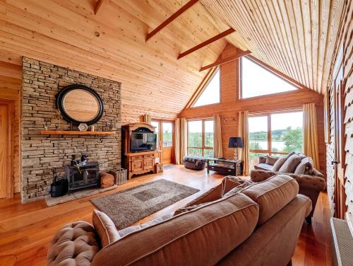 a living room with a couch and a stone fireplace at Fern Lodge. Drumcoura Lake Resort, in Ballinamore