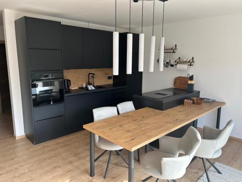 Una cocina con una mesa de madera y sillas blancas. en Zur Stella, en Presseggen