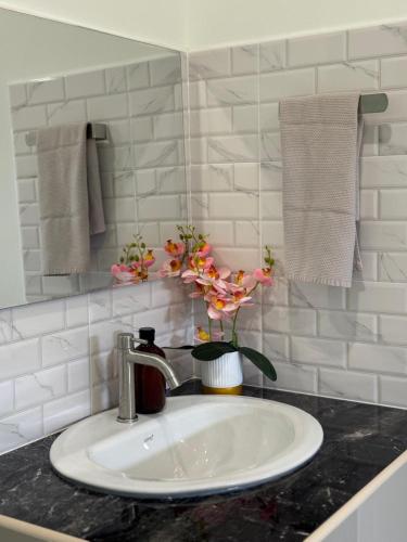 a bathroom sink with a vase of flowers on it at Nong Hoi Nest, New Townhome with Positive Pressure Air Purifier in Chiang Mai