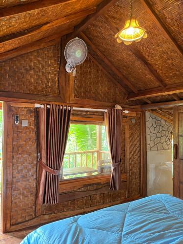 a bedroom with a bed and a window at Ananda Bungalow Tetebatu in Tetebatu
